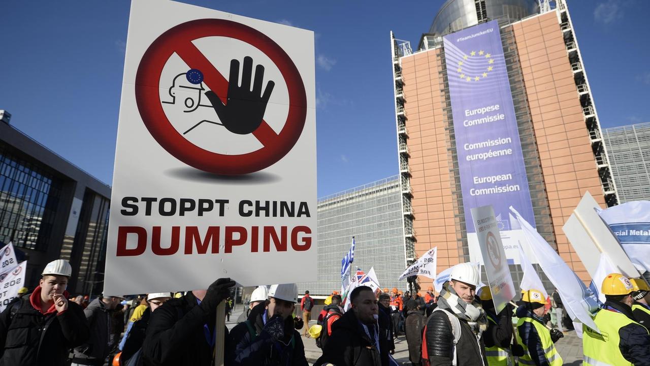 Mitglieder mehrerer Industrie-Gewerkschaften, besonders der Stahlindustrie, halten am 15.02.2016 in Brüssel ein Plakat  mit dem Text "Stoppt China Dumping" hoch, um gegen die Dumpingpreise chinesischer Produkte im europäischen Markt zu protestieren.