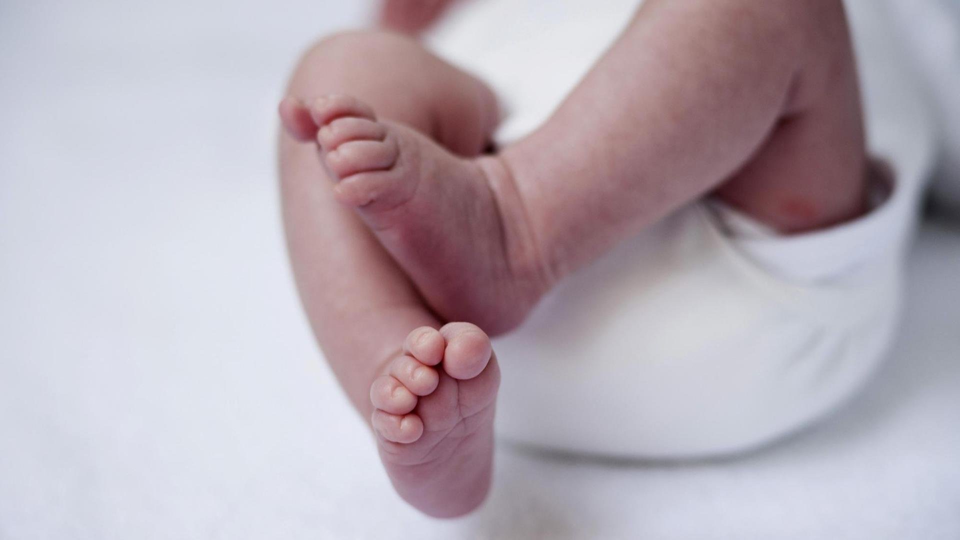 Nackte Füße eines neugeborenen Babys.