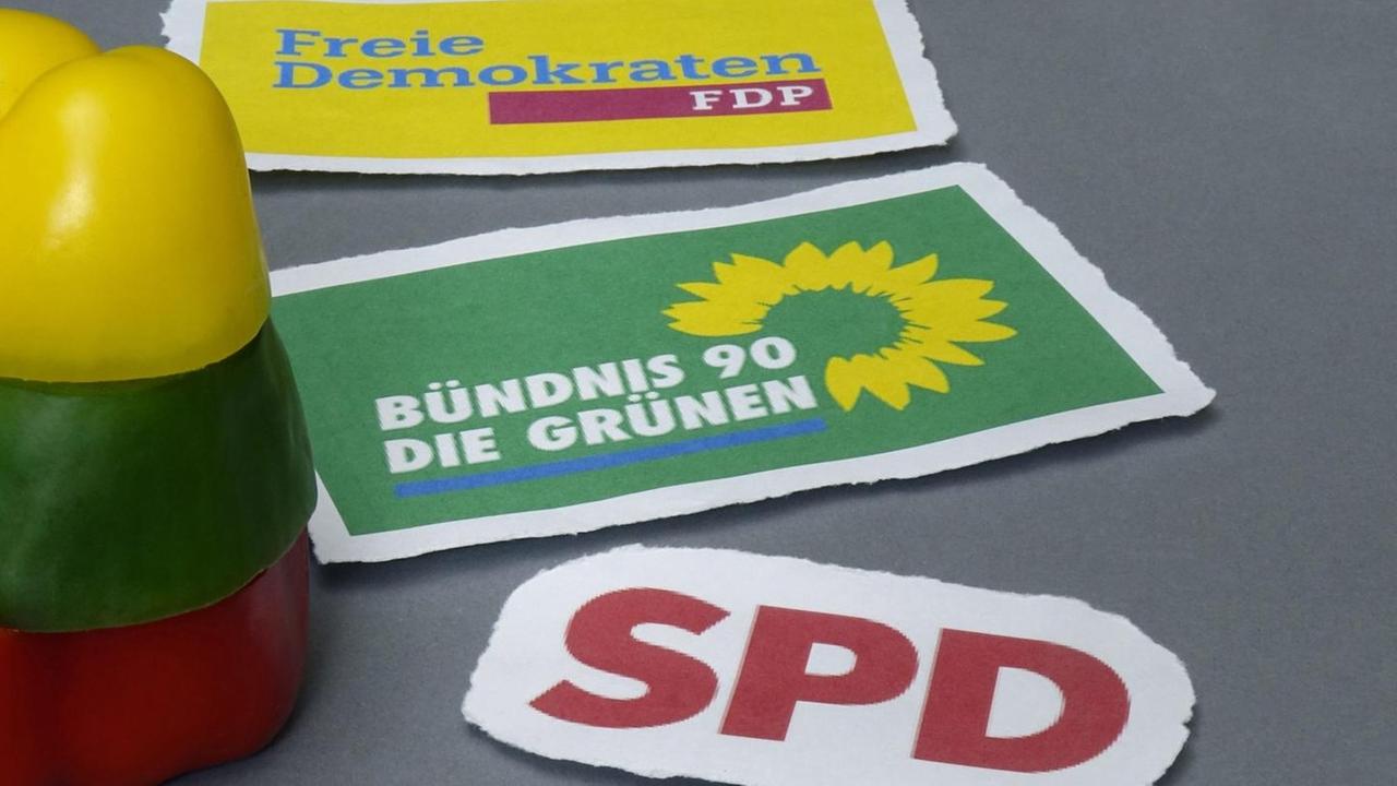Auf einem grauen Untergrund liegen Parteilogos in den Farben einer Ampel Koalition. Auf einem grauen Untergrund liegen Parteilogos in den Farben einer Ampel Koalition.