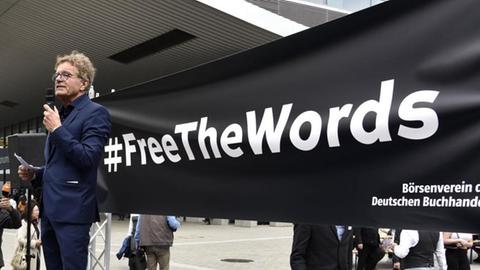 Alexander Skipis bei der Mahnwache FreeHongKong auf der 71. Frankfurter Buchmesse 2019 auf der Messe Frankfurt. Frankfurt am Main, 17.10.2019. Im Hintergrund steht auf einem schwarzen Banner: #FreeTheWords