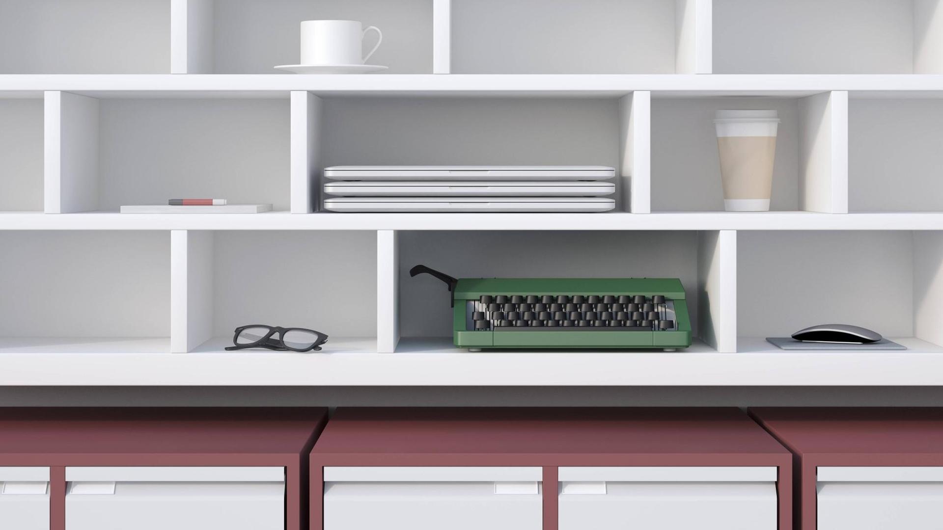 Büroregal mit verschiedenen Utensilien wie Laptops, Schreibmachine, Brille Kaffeetasse