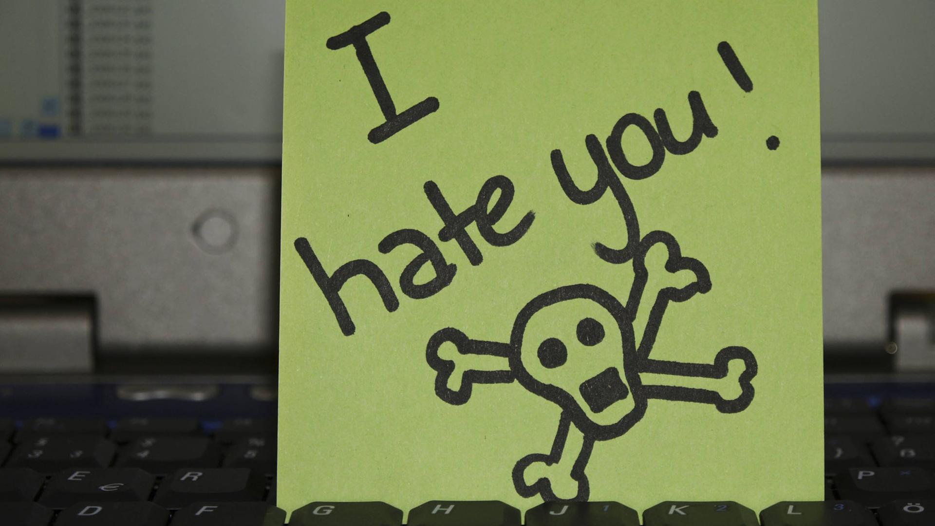 Notizzettel auf Laptop-Tastatur: "I hate you" - Ich hasse dich -, daneben ist ein Totenkopf gezeichnet