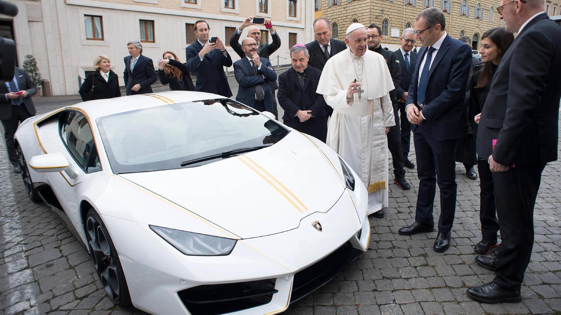 Papst Franziskus spricht mit dem CEO von Lamborghini, Stefano Domenicali, neben einem weißen Sportwagen, einem Geschenk des Unternehmens an den Potifex
