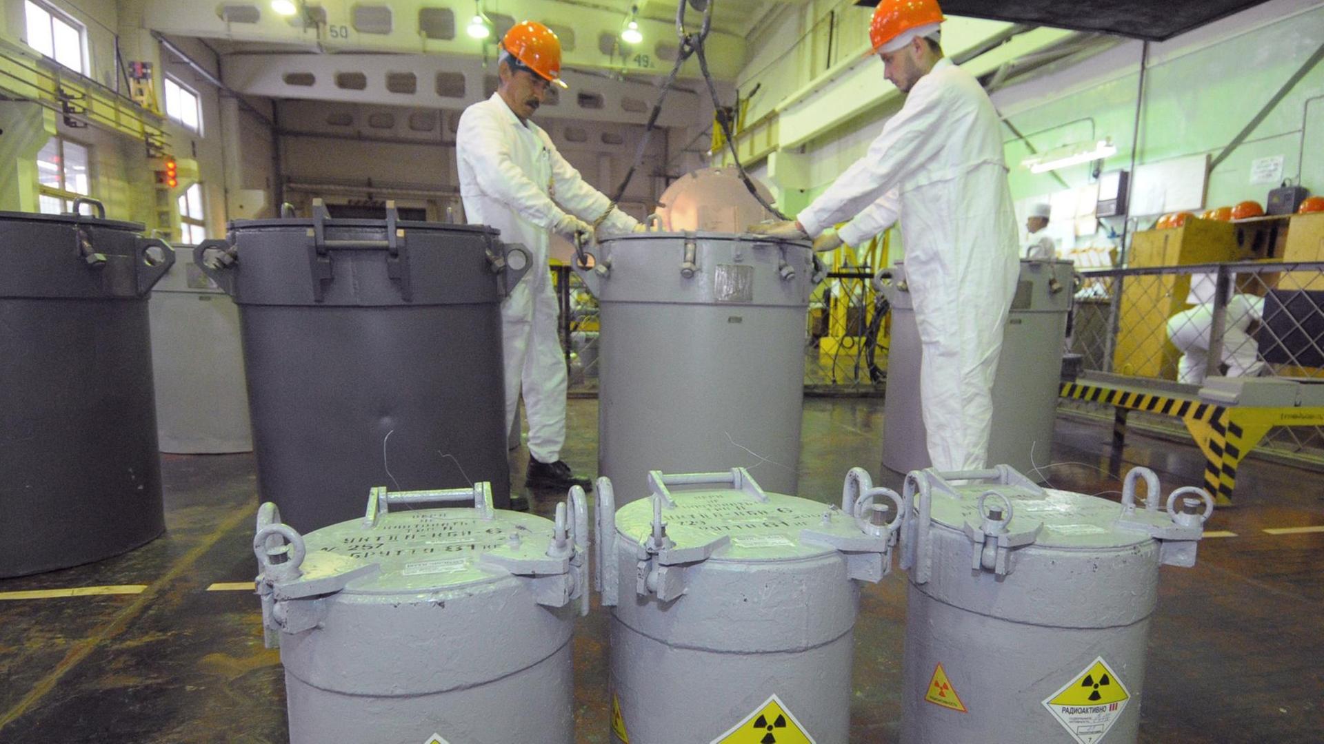 Mitarbeiter in der russischen kerntechnischen Anlage Majak neben Behältnissen, die laut Kennzeichnung radioaktives Material enthalten