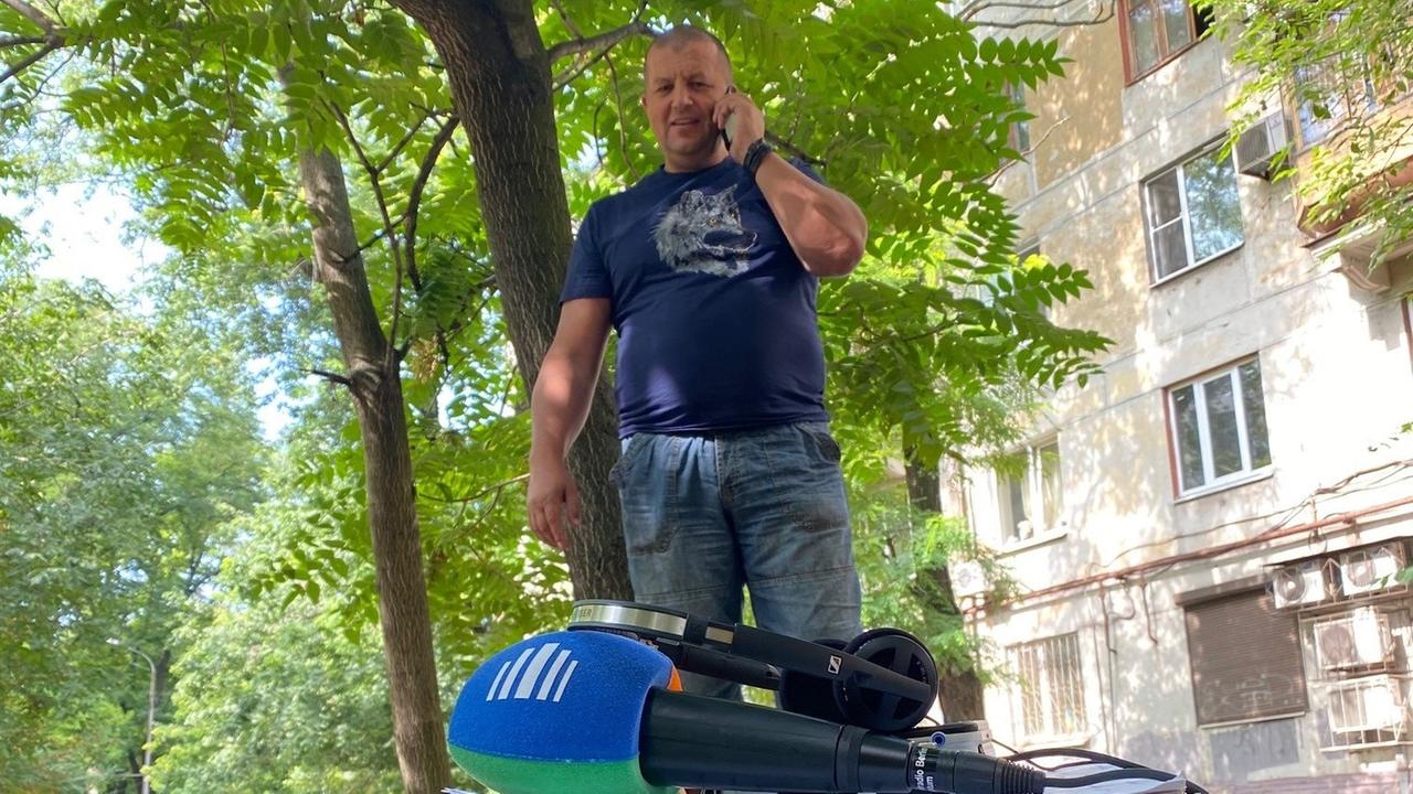Uni-Dozent und Kampfsportler Olexander Pritúla aus Saporischschja: kahlrasierter Kopf, enges blaues T-Shirt, Bauansatz, Handy in der Hand.