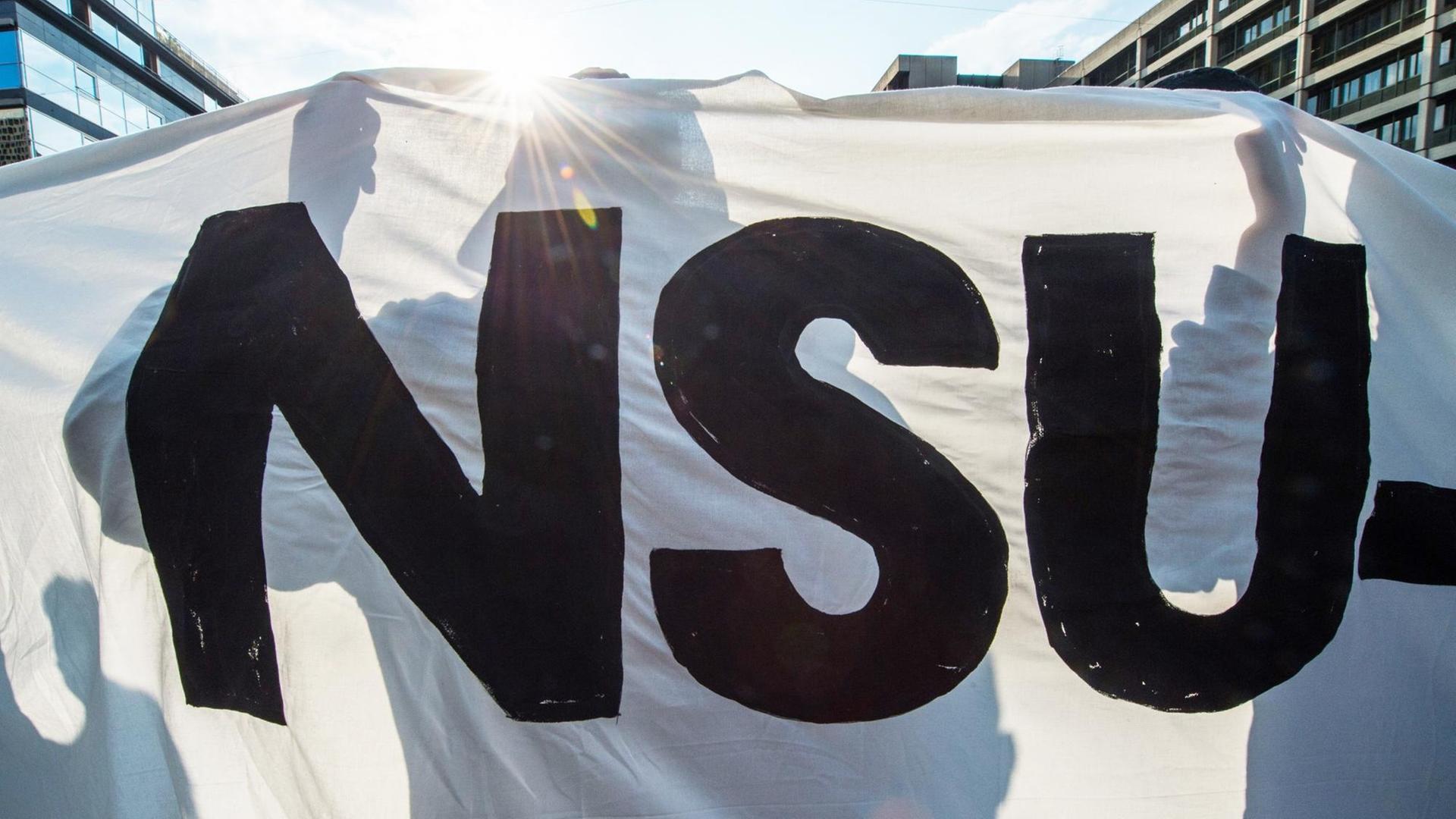 Ein Demonstrant hält bei einer Kundgebung ein Banner mit der Aufschrift "NSU". Ein Demonstrant hält bei einer Kundgebung ein Banner mit der Aufschrift "NSU".