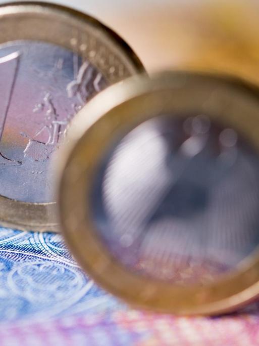 Zwei Ein-Euro-Münzen stehen auf einem Geldschein.