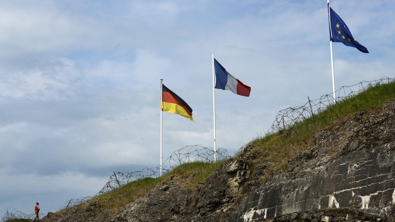 Hinter Stacheldraht wehen auf der ehemaligen französischen Festung Fort Douaumont bei Verdun/Frankreich (Lorraine) die Fahnen Deutschlands (l-r), Frankreichs und der EU, aufgenommen am 25.04.2014.