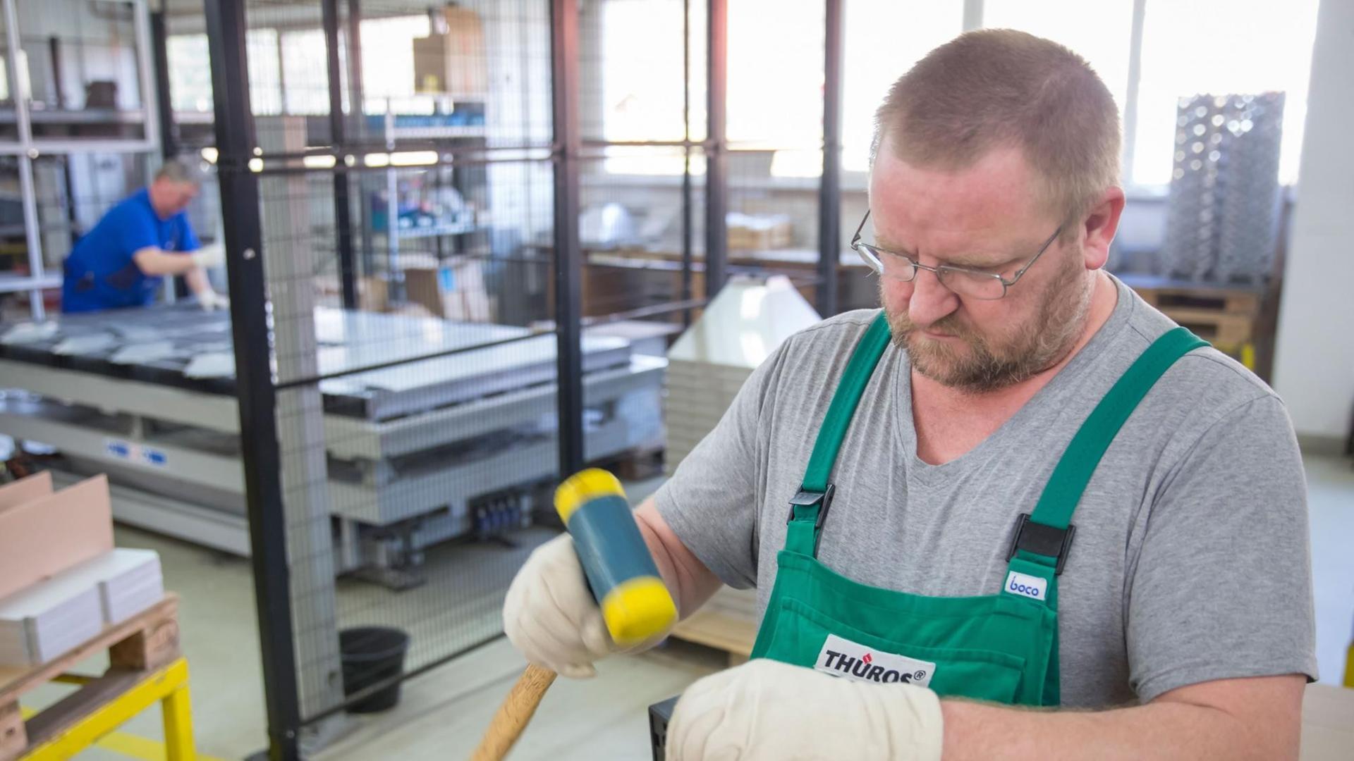 Ein Arbeiter montiert in einer Werkshalle in Thüringen einen Grillrost. Ein Arbeiter montiert in einer Werkshalle in Thüringen einen Grillrost.