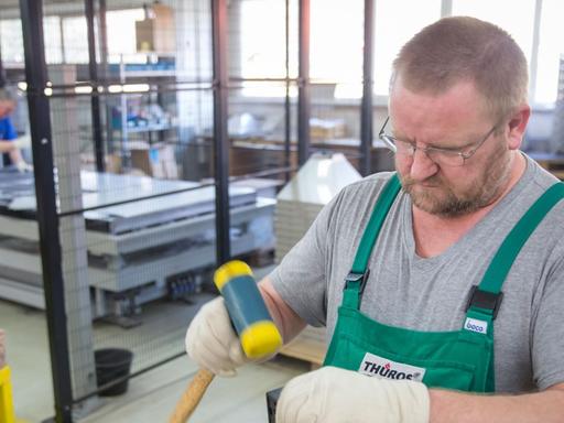 Ein Arbeiter montiert in einer Werkshalle in Thüringen einen Grillrost.