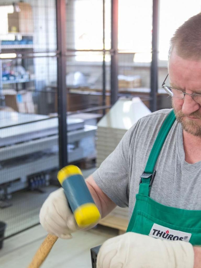 Ein Arbeiter montiert in einer Werkshalle in Thüringen einen Grillrost.