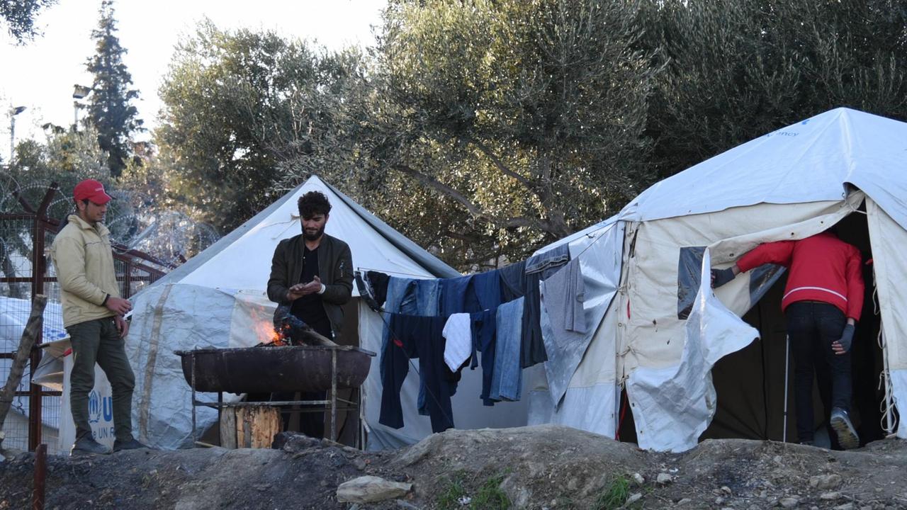 An einem offenen Feuer wärmen sich im Flüchtlingscamp Moria einige Männer die Hände.