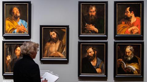 24.10.2019, Bayern, München: Eine Journalistin steht bei der Begehung der Ausstellung «Anthonis van Dyck (1599-1641)» in der Alten Pinakothek vor Heiligendarstellungen von Anthonis van Dyck.