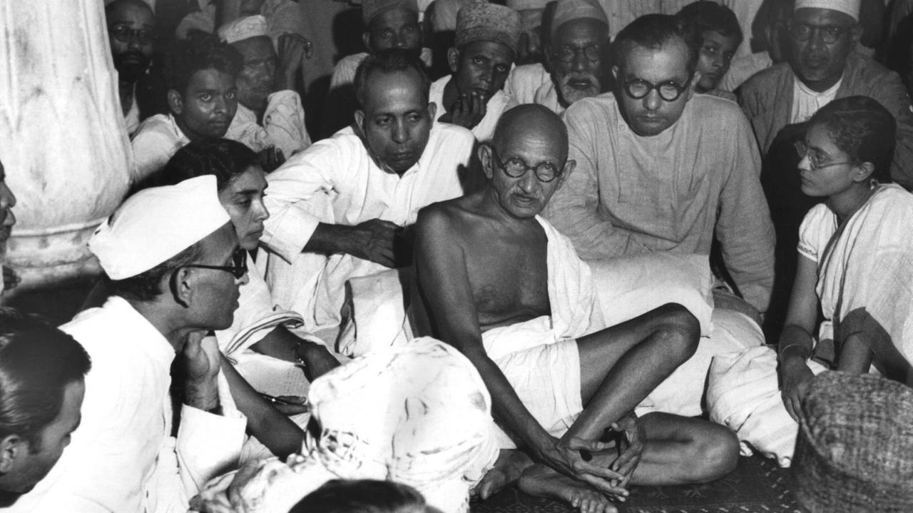 Gandhi sitzt in einer undatierten Aufnahme bei Muslimen in Neu-Delhi und versucht, die blutigen Auseinandersetzungen zwischen den Muslimen und den Hindus zu schlichten.