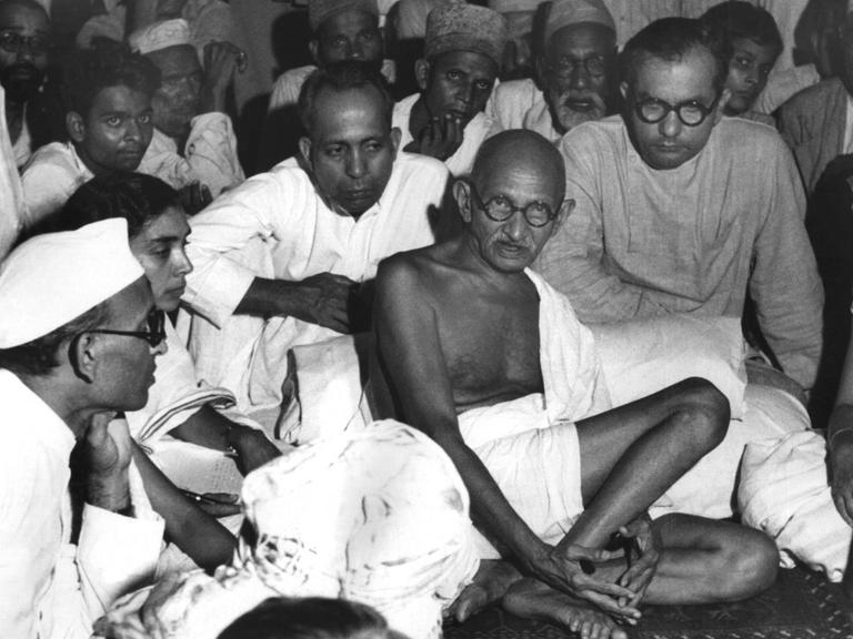 Gandhi sitzt in einer undatierten Aufnahme bei Muslimen in Neu-Delhi und versucht, die blutigen Auseinandersetzungen zwischen den Muslimen und den Hindus zu schlichten.