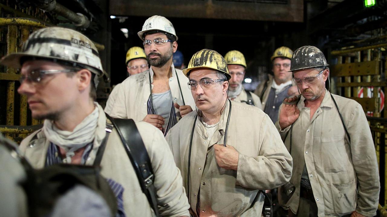 Bergleute in Arbeitskleidung und mit Helmen.