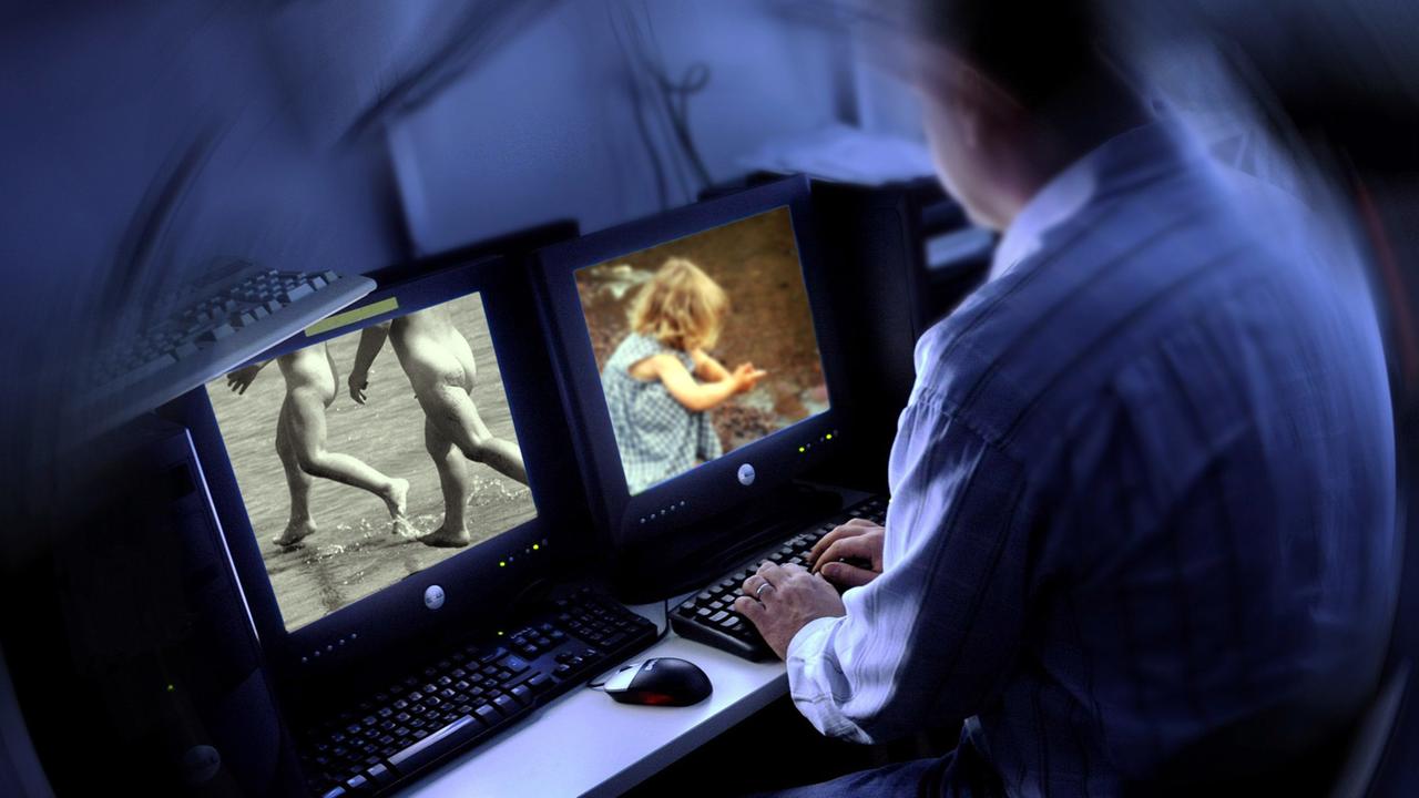 Ein Mann sitzt am Computer und sieht sich Bilder mit Kindern an.
