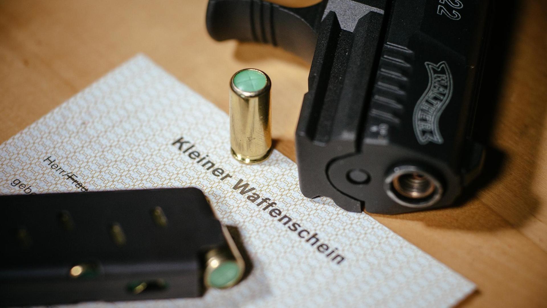 Ein Kleiner Waffenschein liegt zwischen einer Schreckschuss-Pistole "Walther P22", einem Magazin und einer Knallpatrone. Das Dokument berechtigt den Besitzer zum Tragen einer solchen Waffe in der Öffentlichkeit.