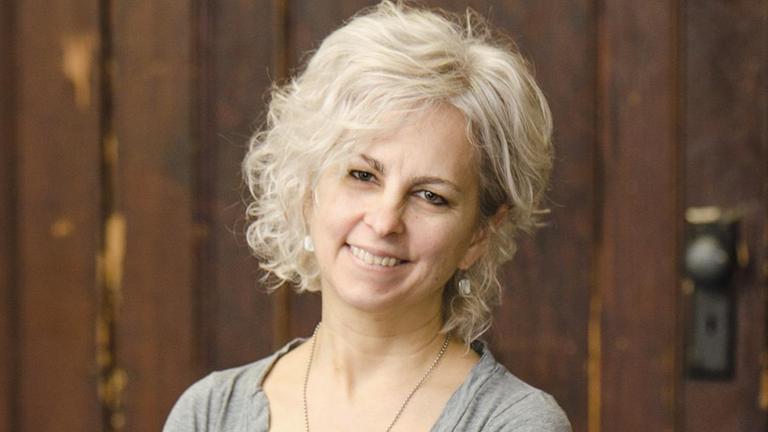 Kate DiCamillo sitzt auf einem Stuhl und lächelt in die Kamera.