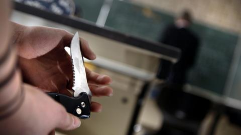 Eine Schülerin zeigt während des Unterrichts einer Mitschülerin ihr Klappmesser