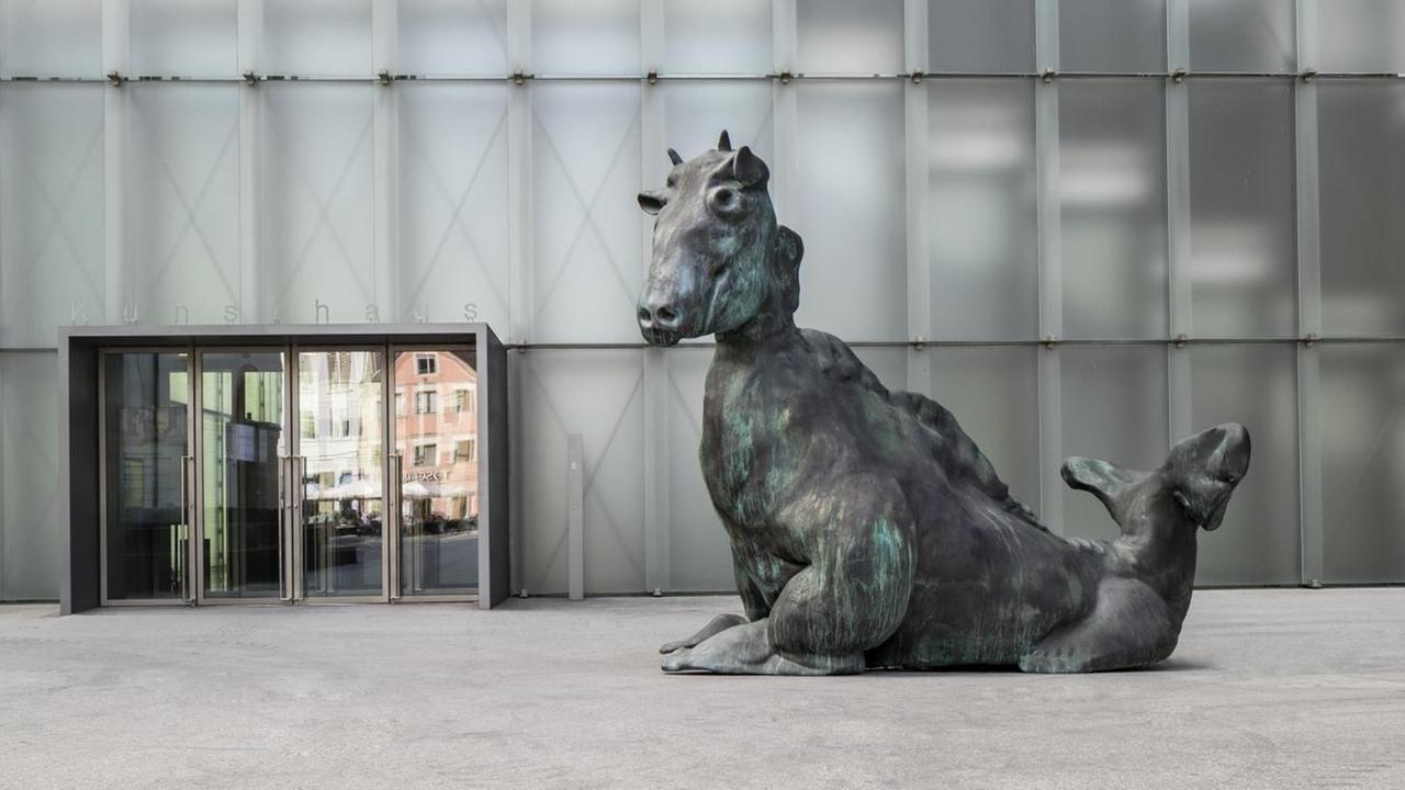 Zu sehen ist Thomas Schüttes Skulptur "Drittes Tier" vor der Fassade des Bregenzer Kunsthauses: ein grünlich patiniertes, über drei Meter hohes Fabelwesen aus Bronze.