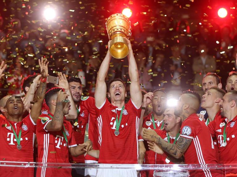 Stürmer Robert Lewandowski hält, umringt von der restlichen Mannschaft Bayern Münchens, den DFB-Pokal in die Höhe.