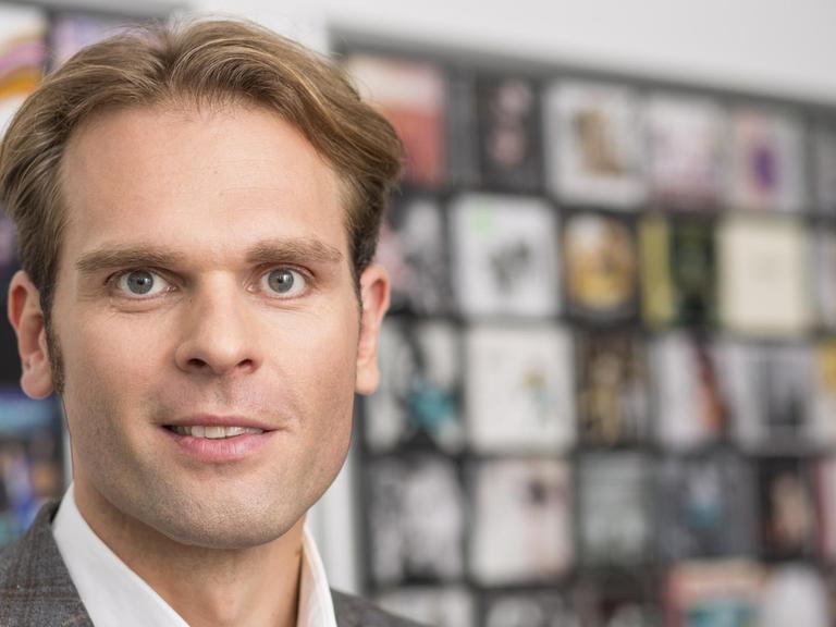 Florian Drücke, Geschäftsführer vom Bundesverband Musikindustrie e.V. vor einem unscharfen Regal voller Tonträger.