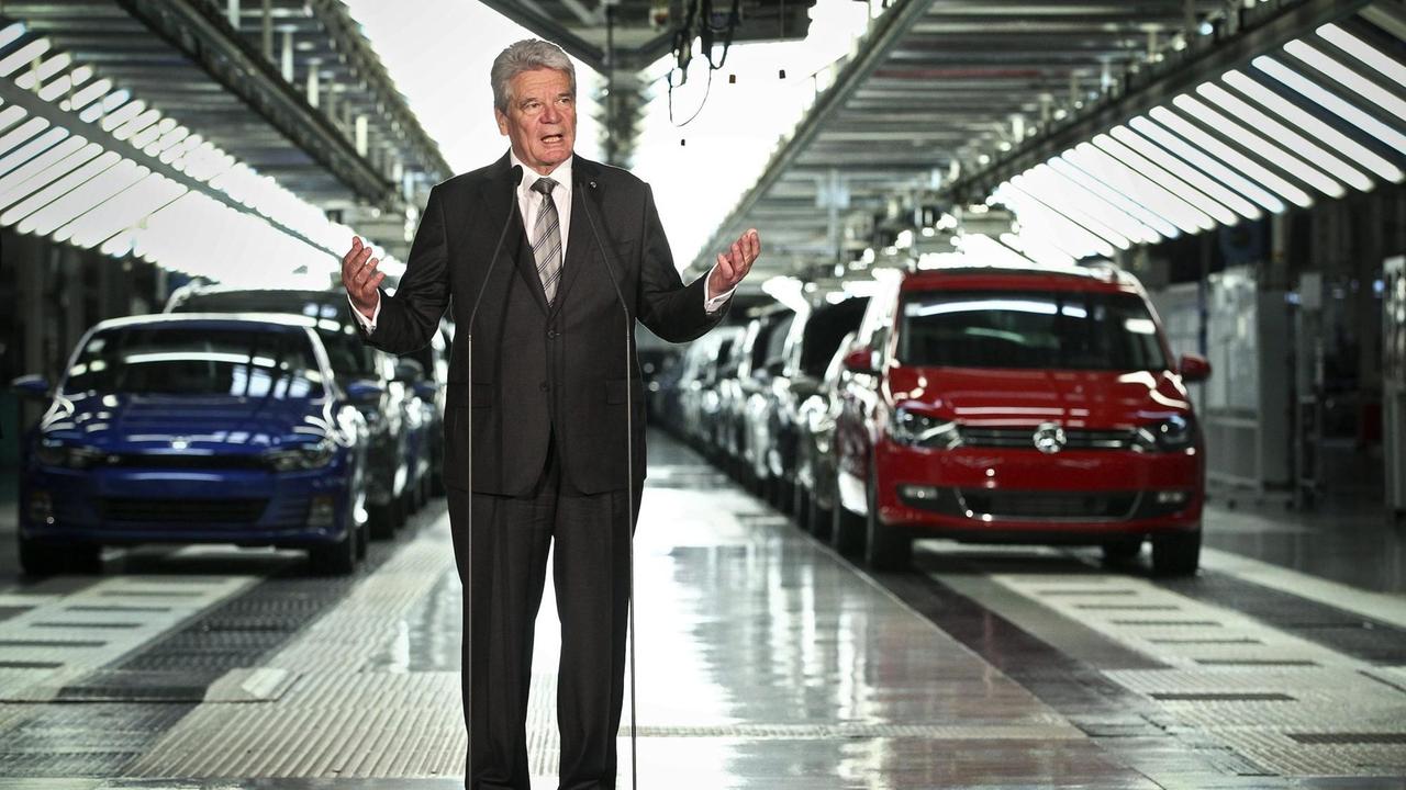 Joachim Gauck steht vor zwei Reihen von Autos an einem Mikrofon und spricht.