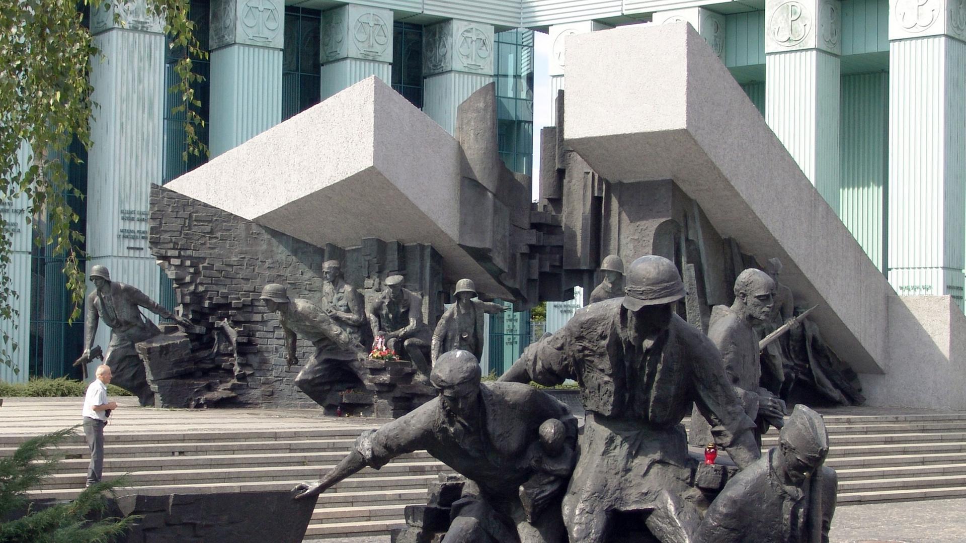 Das Bild zeigt das Denkmal für den Warschauer Aufstand in Warschau, im Vordergrund ein Blumenbeet.