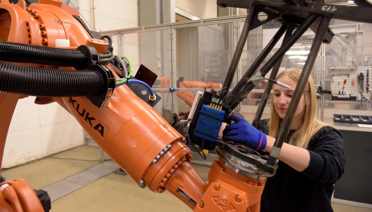 Mitarbeiterin beim Maschinenbauer KUKA mit einem Roboter Foto: Stefan Puchner/dpa | Verwendung weltweit