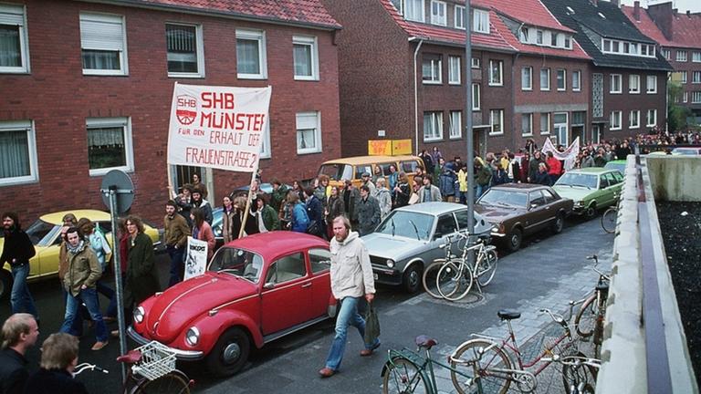 Demonstranten tragen ein Transparent mit der Aufschrift "SHB Münster - Erhalt der Frauenstrasse 24".