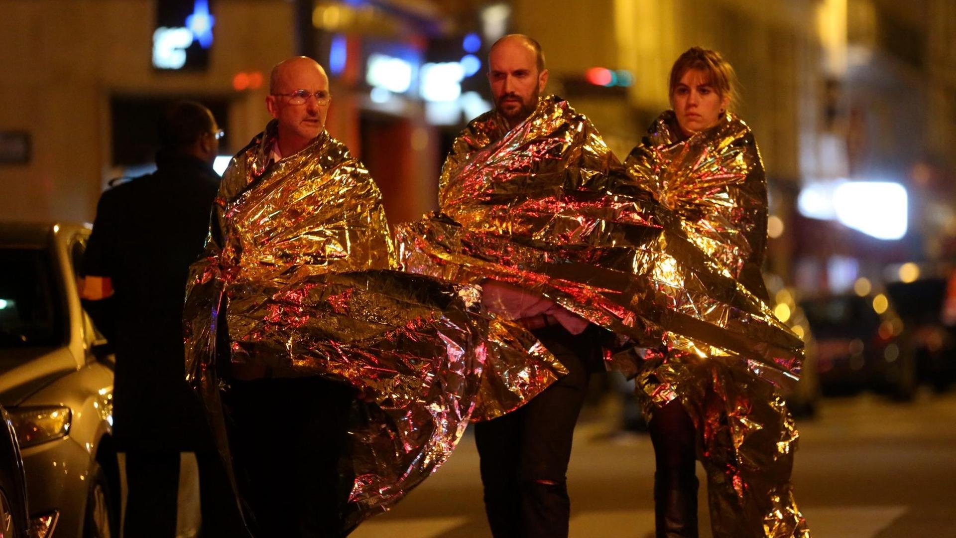 Nach den Anschlägen von Paris stehen Menschen in Notdecken gehüllt auf der Straße.