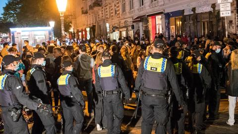 Polizisten treiben am späten Abend Besucher aus dem Schanzenviertel. Nachdem sich zahlreiche Menschen in Parks und auf den Straßen versammelt hatten, hat die Polizei das Viertel am Abend geräumt und Geschäfte und Gastronomie eher schließen lassen.