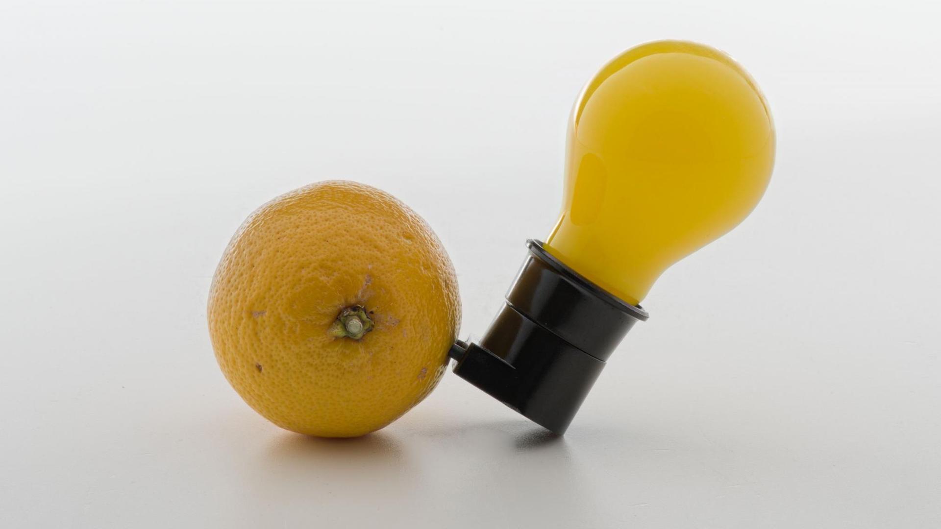 Eine gelbe Glübirne steckt in einer Zitrone.
