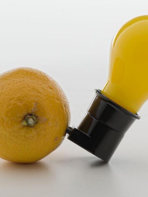 Eine gelbe Glübirne steckt in einer Zitrone.