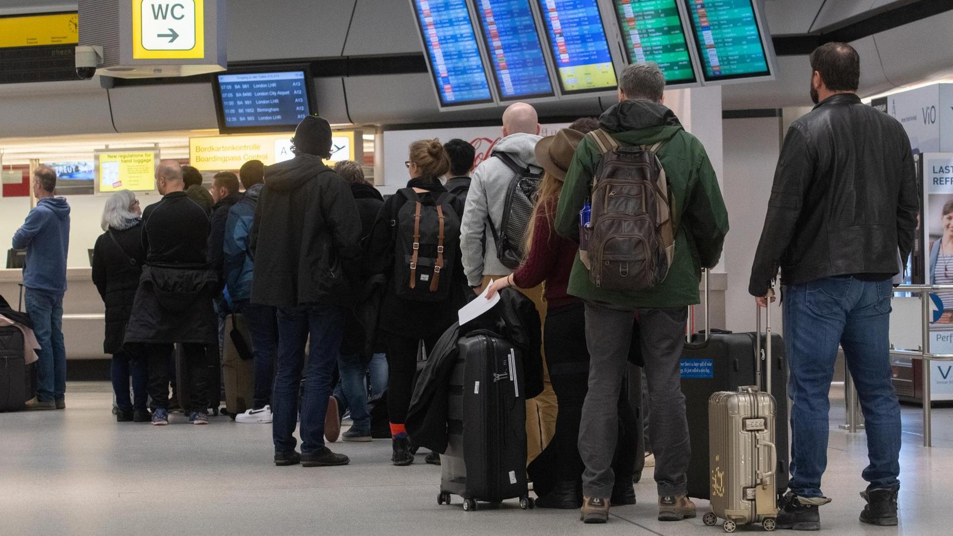Das Foto zeigt Reisende, die an einem Schalter am Flughafen anstehen.