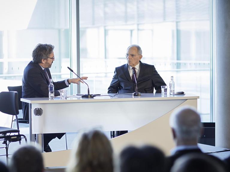 Stephan Detjen und Wolfgang Schäuble sitzen an einem Tisch vor Publikum