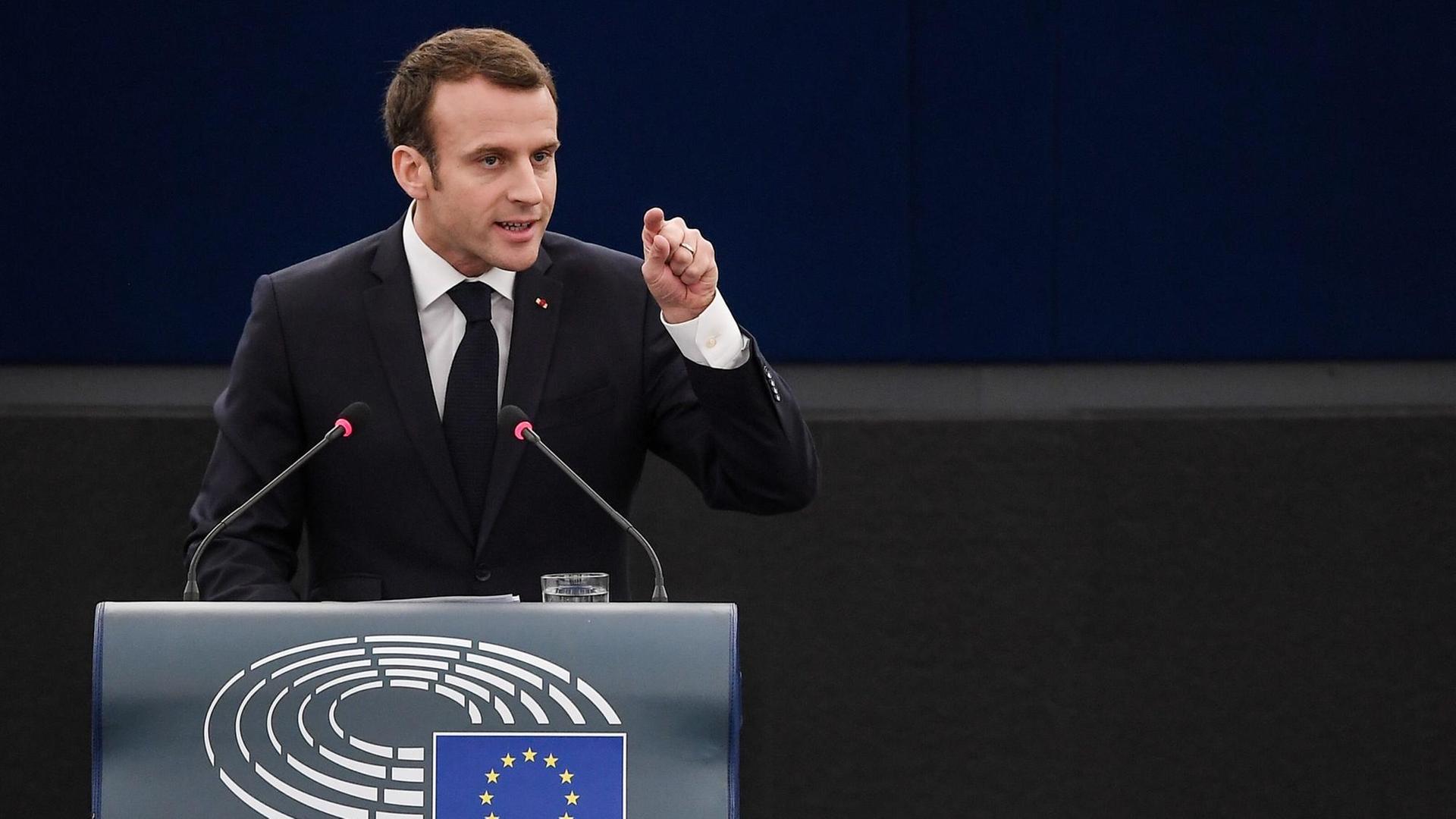 Macron steht am Rednerpult und zeigt mit dem linken Zeigefinger in Richtung der Abgeordneten.