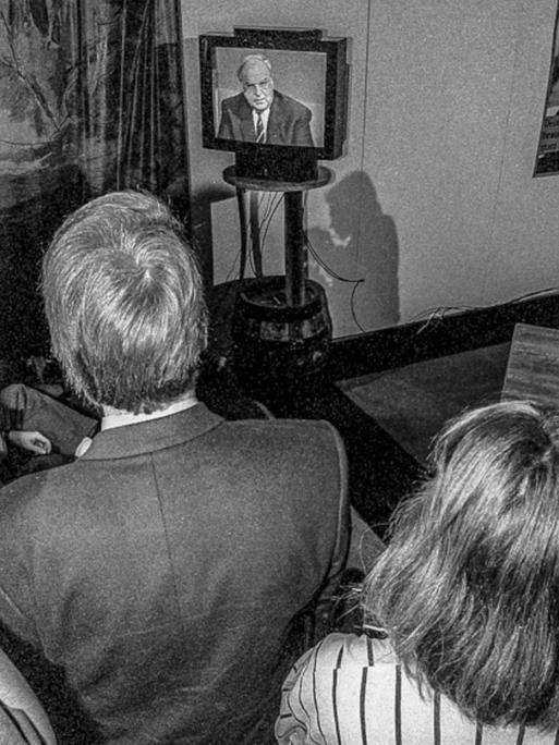 Teilnehmer der Wahlparty der CDU/CSU sehen auf einem Fernsehapparat die Rede von Helmut Kohl.