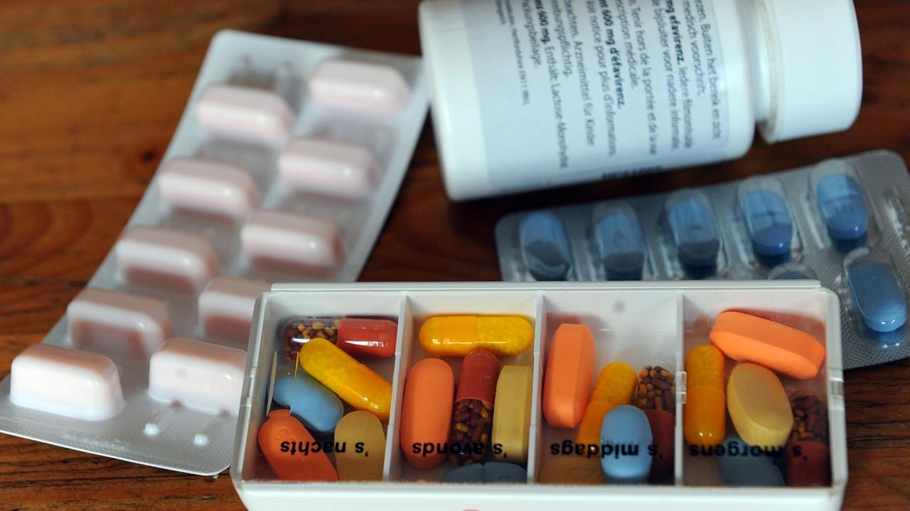 Tabletten liegen in Tagesrationen und in Blistern sowie einer Dose auf einem Tisch.