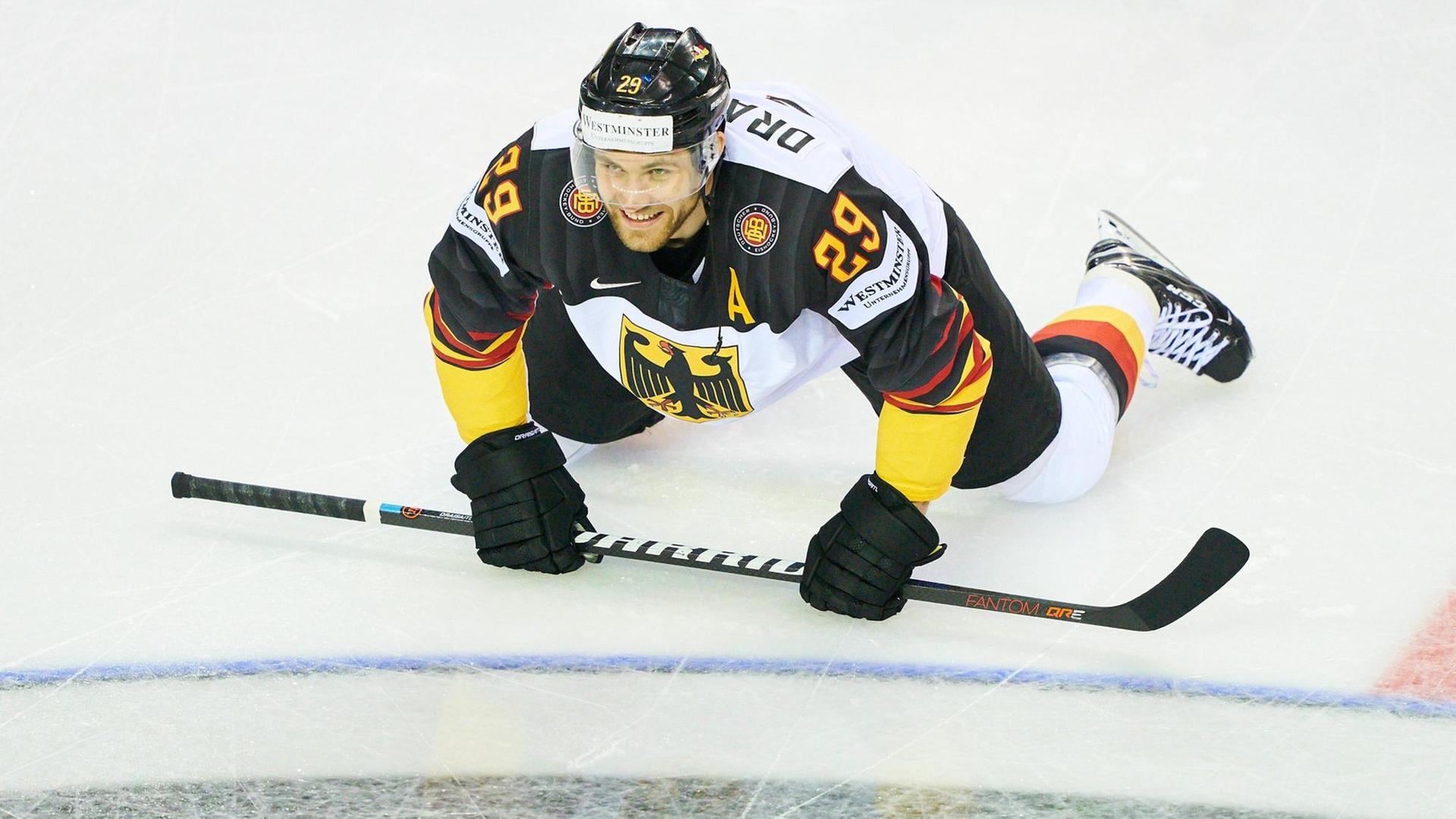 Leon Draisaitl sitzt auf dem Eis und hält seinen Hockey-Schläger vor sich.