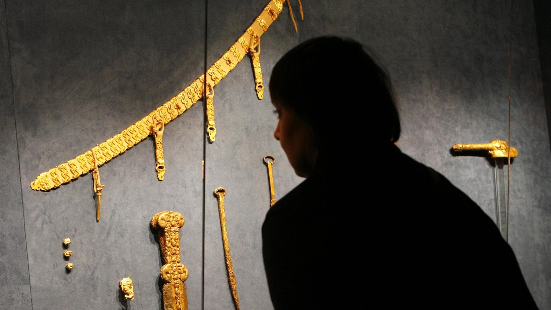 Eine Besucherin schaut sich am Mittwoch (13.02.2008) im Museum für Kunst und Gewerbe in Hamburg Schmuck eines Fürstenpaares der Skythen aus dem 7. Jahrhundert nach Christus an.