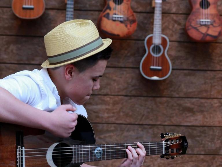 Ein Junge speilt auf der Frankfurter Musikmesse 2017 eine Gitarre.