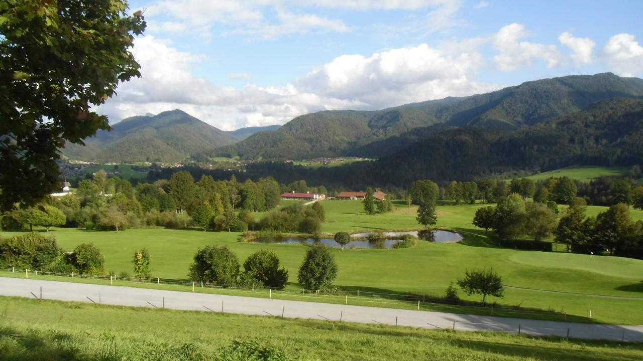 Ansicht von Reit im Winkl, eine Golfanlage im Vordergrund, im Hintergrund die Berge