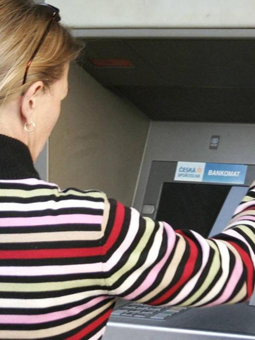 Eine Frau hebt Geld an einem Bankautomaten in Tschechien ab