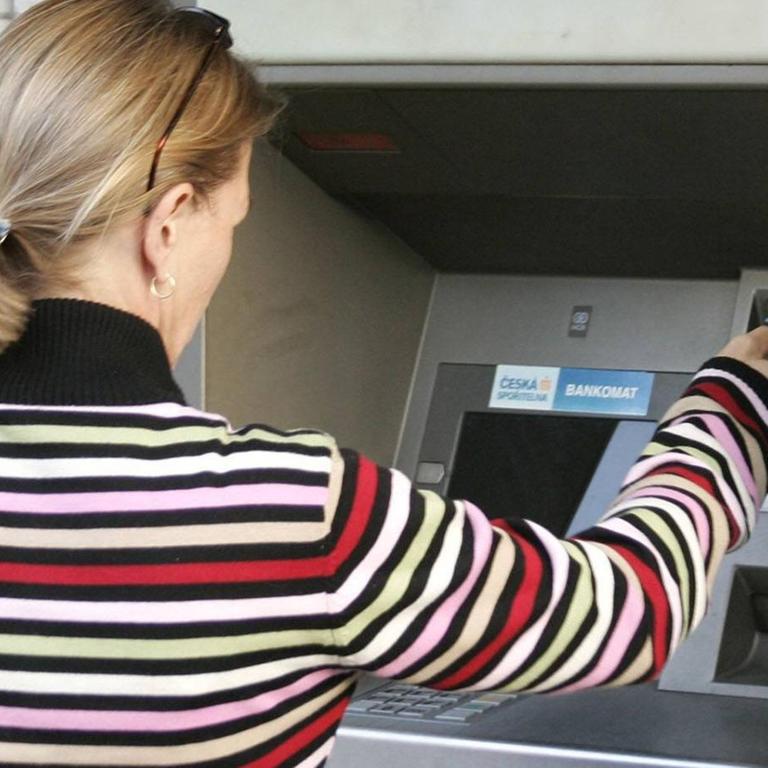 Eine Frau hebt Geld an einem Bankautomaten in Tschechien ab