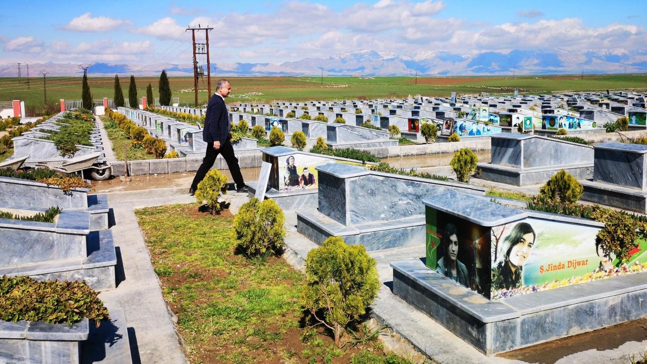 Ein Mann schreitet über einen riesigen Friedhof.