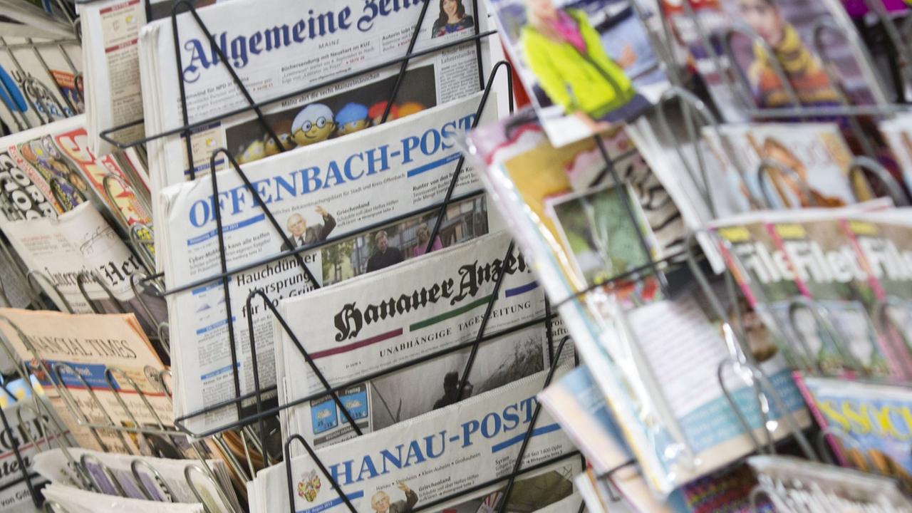 Tageszeitungen stecken an einem Zeitungsstand in Drehständern.