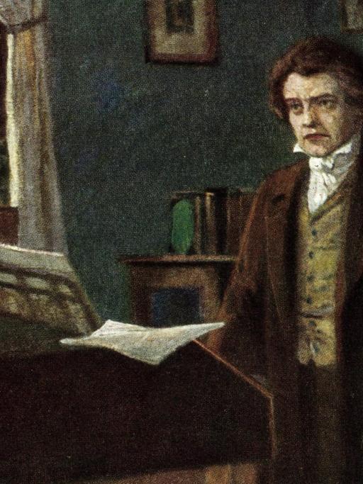 Komponist Ludwig van Beethoven steht in einem Zimmer mit einem Flügel im Hintergrund.