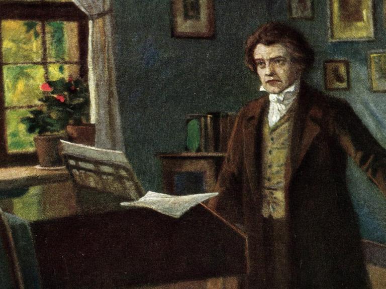 Komponist Ludwig van Beethoven steht in einem Zimmer mit einem Flügel im Hintergrund.